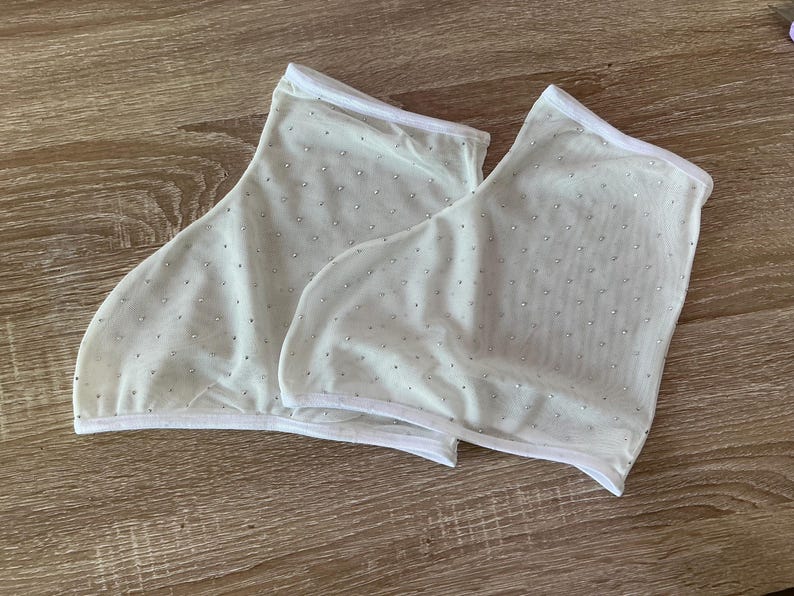 May include: A pair of off-white sheer mesh ankle socks featuring a scattered pattern of small, reflective silver rhinestones throughout the fabric. Each sock is finished with a clean white hem along the top and bottom edges for structure.