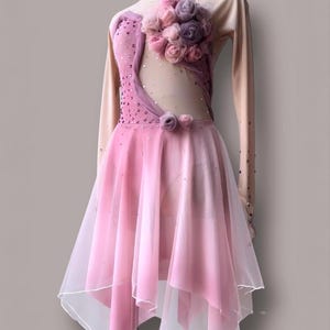 May include: A long-sleeved performance dress featuring a nude-colored mesh bodice with pink fabric panels, scattered crystals, and a cluster of pink and purple fabric roses on the chest. The skirt is made of layered pink sheer fabric.