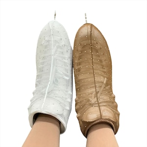 May include: A pair of ice skate covers, one white and one tan, made of a sheer mesh fabric. Each cover features a vertical seam down the center and is embellished with small, evenly spaced silver rhinestones across the entire surface.