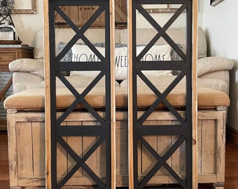 May include: Two black and white wooden wall decor pieces with a criss-cross design. The pieces are framed in white and have a distressed wood finish.