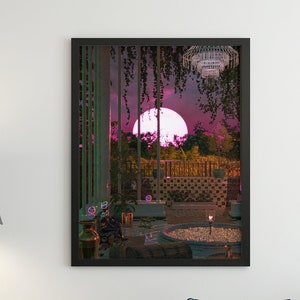 May include: A black framed print of a digital illustration depicting a moonlit outdoor scene with a round pool of water, a chandelier, and a fence. The scene is framed by a window with vines growing over it. The print is hanging on a white wall above a dark blue sofa with a white pillow.