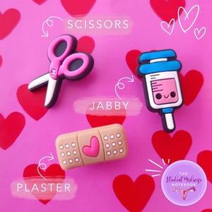 May include: Pink, blue, and brown medical themed shoe charms with the words "Scissors", "Jabby", and "Plaster" on a pink background with hearts. The charms are from The Student Midwife Notebook.