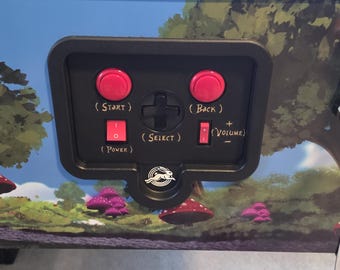 Superposición del panel de control de la mesa de pinball de Alicia en el País de las Maravillas. Añade un toque de encanto con etiquetas cuidadosamente colocadas en el panel de control.