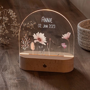 Könnte beinhalten: Eine Holz-Nachtlampe mit einem klaren Acryl-Bogen, der mit einem Blumendesign und dem Text "ANNIE 02. JUNI 2023" verziert ist.