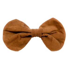 以下が含まれることがあります： 茶色のコーデュロイのリボン。リボンはシンプルな結び目で結ばれており、わずかにテクスチャのある表面をしています。