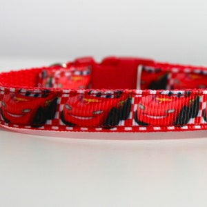 May include: Red and white dog collar with a repeating pattern of Lightning McQueen from the Disney Pixar movie Cars.