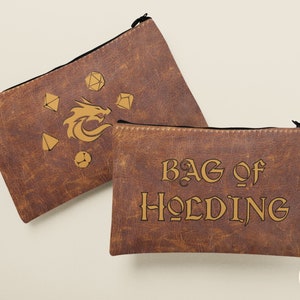 May include: Two brown leather zippered pouches with gold embroidery. One pouch features a dragon and dice, the other says "Bag of Holding".