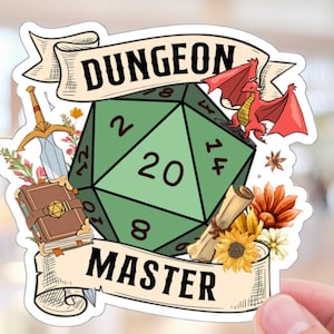 Puede incluir: Un dado verde de 20 caras con un dragón rojo, una espada, un libro y flores. El dado está rodeado de una pancarta que dice "Dungeon Master".