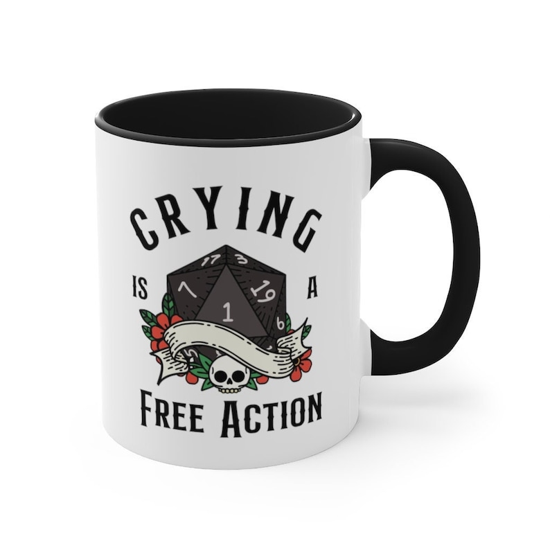 May include: White ceramic mug with a black handle and rim. The mug has a black and white illustration of a 20-sided die with the text "Crying is a Free Action".