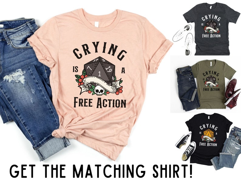 May include: A pink t-shirt with a black and white graphic of a dice with the text "CRYING IS A FREE ACTION".