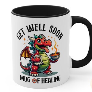 May include: White ceramic mug with a black handle and rim. The mug features a cartoon red dragon holding a steaming bowl. The text "Get Well Soon Mug of Healing" is printed on the mug.