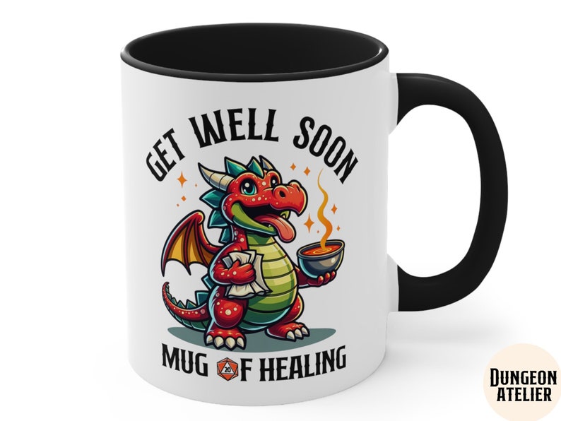 May include: White ceramic mug with a black handle and rim. The mug features a cartoon red dragon holding a steaming bowl. The text "Get Well Soon Mug of Healing" is printed on the mug.