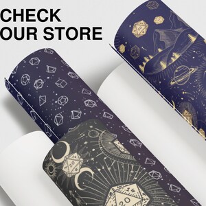 May include: Three different patterned wrapping paper rolls with a celestial theme. The patterns feature dice, stars, moons, and planets in gold and white on a dark blue background.