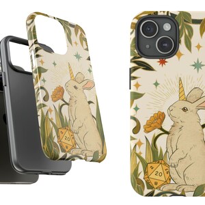 May include: A phone case featuring a whimsical illustration of a rabbit with a unicorn horn, standing in a field with a 20-sided die. The design includes flowers, stars, and foliage in a vintage style, with a cream-colored background.