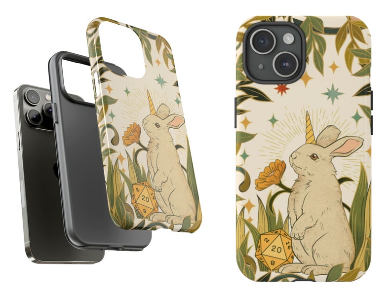 May include: A phone case featuring a whimsical illustration of a rabbit with a unicorn horn, standing in a field with a 20-sided die. The design includes flowers, stars, and foliage in a vintage style, with a cream-colored background.
