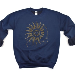 Puede incluir: Sudadera azul marino con un dise&ntilde;o dorado de sol y luna, que incorpora una forma geom&eacute;trica. El dise&ntilde;o presenta detalles intrincados y un tema celestial. La sudadera tiene cuello redondo y mangas largas.