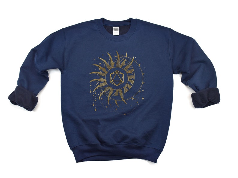 Puede incluir: Sudadera azul marino con un dise&ntilde;o dorado de sol y luna, que incorpora una forma geom&eacute;trica. El dise&ntilde;o presenta detalles intrincados y un tema celestial. La sudadera tiene cuello redondo y mangas largas.