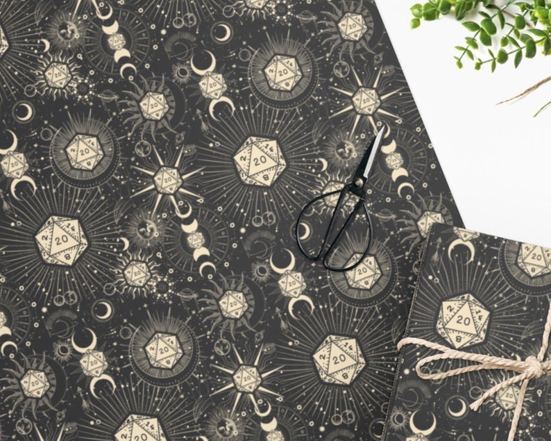 May include: Black and white wrapping paper with a repeating pattern of dice, moons, and stars. The dice are 20-sided and have the number 20 on them. The moons are crescent shaped and the stars are small and scattered.