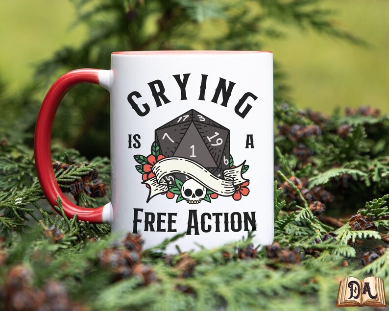 May include: White ceramic mug with a red handle. The mug has a black and white illustration of a 20-sided die with the text "Crying is a Free Action".