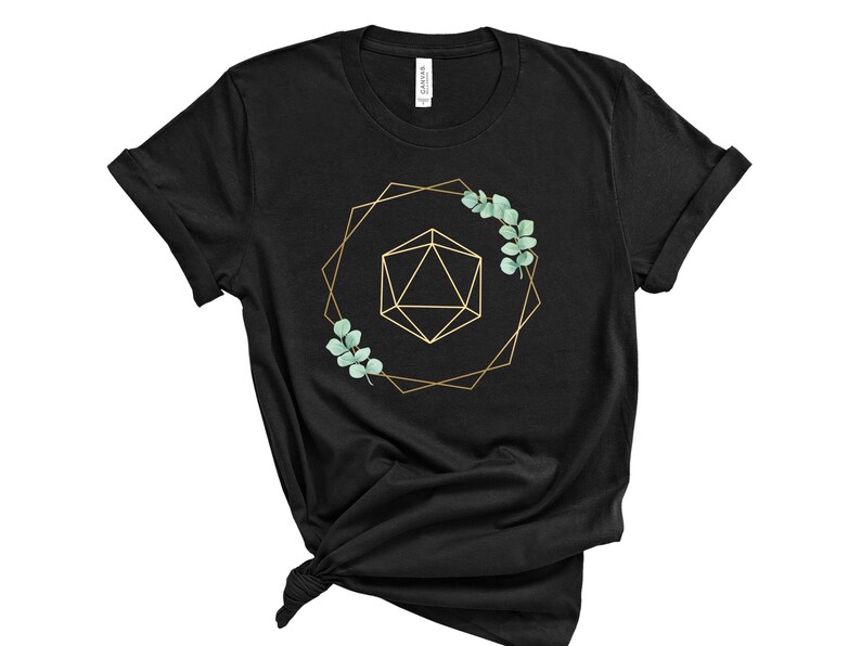 May include: Black t-shirt featuring a gold geometric design with a 20-sided die and eucalyptus leaves. The design is framed by a gold geometric shape. The shirt is made of a soft material.