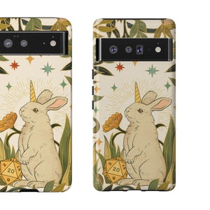 May include: A phone case featuring a whimsical illustration of a rabbit with a unicorn horn, surrounded by flowers and foliage. The design includes a 20-sided die. The case has a cream background with a decorative border.