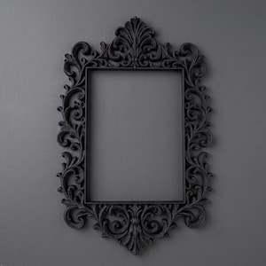 May include: A rectangular picture frame in a matte black finish featuring an ornate, raised scrollwork and acanthus leaf pattern surrounding the central opening. The frame has a symmetrical design with a prominent decorative crest at the top.
