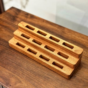 May include: A wooden organizer with multiple tiers and rectangular slots. The organizer is made of light brown wood and has a natural finish.