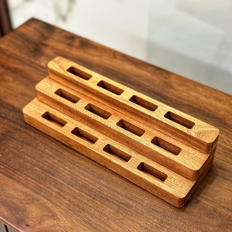 May include: A wooden organizer with multiple tiers and rectangular slots. The organizer is made of light brown wood and has a natural finish.