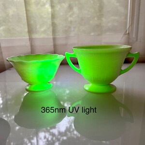 May include: Two vintage green glass bowls, one with a scalloped edge and the other with two handles, glowing under a 365nm UV light.