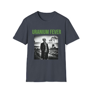 May include: A dark blue t-shirt with a green graphic print of a skeleton in a suit standing in front of a factory with smoke stacks. The text "URANIUM FEVER" is printed above the graphic.