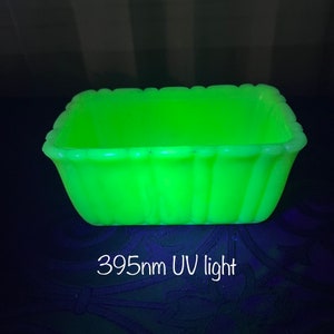 Op de afbeelding: Een heldergroene, rechthoekige glazen schaal met een geribbelde rand. De schaal wordt belicht met een 395 nm UV-licht.