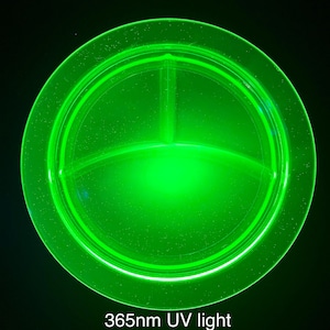 May include: A round, divided plate glows bright green under 365nm UV light. The plate is divided into three sections and has a raised rim. The text "365nm UV light" is at the bottom of the image.
