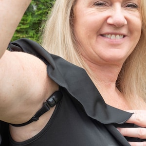 May include: A black underarm sweat shield with an adjustable strap. The shield is worn under clothing to help prevent sweat stains.