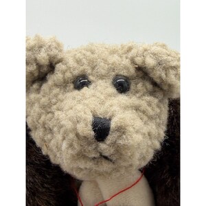 May include: A white ceramic mug with a black handle and the text "But First, Coffee" in a bold, black font. The mug is set against a blurred background, suggesting a cozy setting.