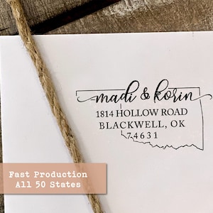 May include: A black and white return address stamp with the text "madi & korin", "1814 HOLLOW ROAD", "BLACKWELL, OK", and "74631". The stamp is shaped like the state of Oklahoma.