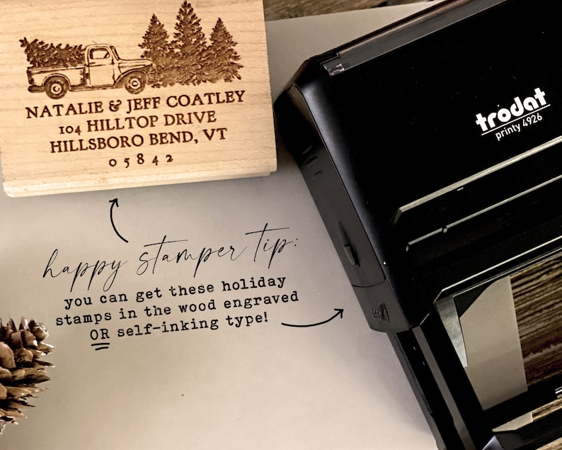 Puede incluir: Un sello de madera con un dise&ntilde;o de cami&oacute;n y &aacute;rbol de Navidad. El sello dice "NATALIE & JEFF COATLEY 104 HILLTOP DRIVE HILLSBORO BEND, VT 05842". El sello est&aacute; al lado de un sello autoentintable Trodat printy 4926 negro.
