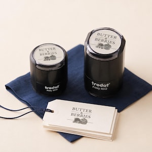 May include: Two black Trodat Printy self-inking stamps, models 4045 and 4642, featuring the text "BUTTER & BERRIES" with a small graphic. A stack of white rectangular paper tags with the same "BUTTER & BERRIES" text and graphic is included.