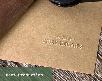Könnte beinhalten: Nahaufnahme eines braunen Lederjournals mit einer goldenen, geprägten Inschrift, die "ex libris LUKE HOLMES" lautet.