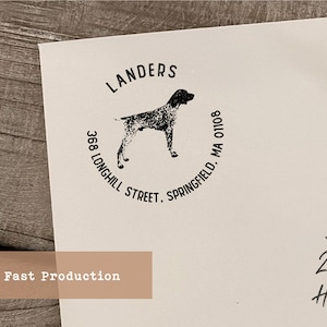 May include: A white paper with a black ink stamp featuring a dog silhouette. The stamp includes the name "Landers", address, and city. The words "Fast Production" are printed on a tan rectangle.