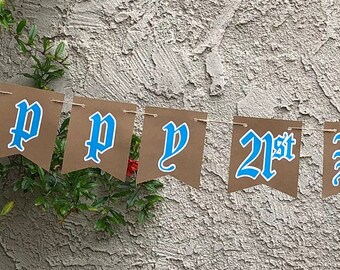 May include: A brown banner with the words "Happy 2nd Birthday" in blue gothic lettering. The banner is decorated with two beer mug cutouts, one on each end. The banner is hanging against a textured wall.