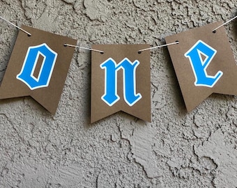 Oktoberfest First Birthday Banner. "ONE" - Brown pennants with blue-white letters -  banner.