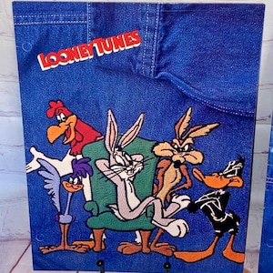 Puede incluir: Un fondo de mezclilla azul con las palabras "Looney Tunes" en rojo. Bugs Bunny, Pato Lucas, Piolín, Correcaminos y el Coyote son representados en un estilo de dibujos animados.