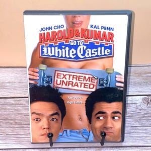 May include: DVD case for the movie "Harold & Kumar Go to White Castle" featuring John Cho and Kal Penn. The cover art includes the film's title, actors' names, and the text "Extreme Unrated". The tagline reads "Fast Food. High Times."