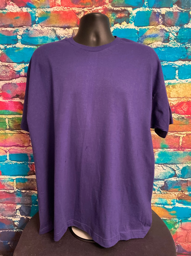 May include: A plain, solid purple t-shirt with short sleeves and a crew neck.