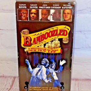 May include: A VHS tape case for the film "Bamboozled" by Spike Lee. The case has a black background with a yellow and white title and a photo of the main actors. The actors listed on the case are Damon Wayans, Savion Glover, Jada Pinkett-Smith, Tommy Davidson, and Michael Rapaport.