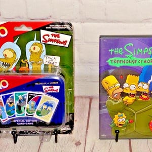 May include: A Simpsons themed UNO card game and a DVD of The Simpsons Treehouse of Horror. The UNO card game is in a tin with a picture of Bart Simpson on the front. The DVD is in a plastic case with a picture of Homer, Bart, Marge, and Lisa Simpson on the front.