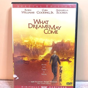 May include: DVD case for the movie "What Dreams May Come" featuring Robin Williams, Cuba Gooding Jr., and Annabella Sciorra. The cover art depicts a man walking with a dog towards a city with a golden sky. The DVD case is labeled "Special Edition".