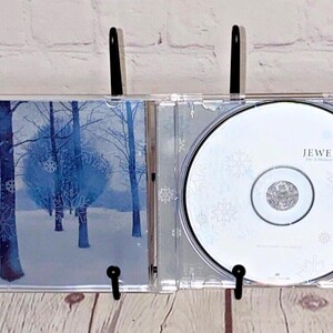 May include: A Jewel CD in a clear plastic case with a wintery forest scene on the front and the text "Jewel - This Way" on the back.