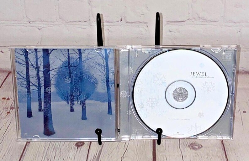 May include: A Jewel CD in a clear plastic case with a wintery forest scene on the front and the text "Jewel - This Way" on the back.