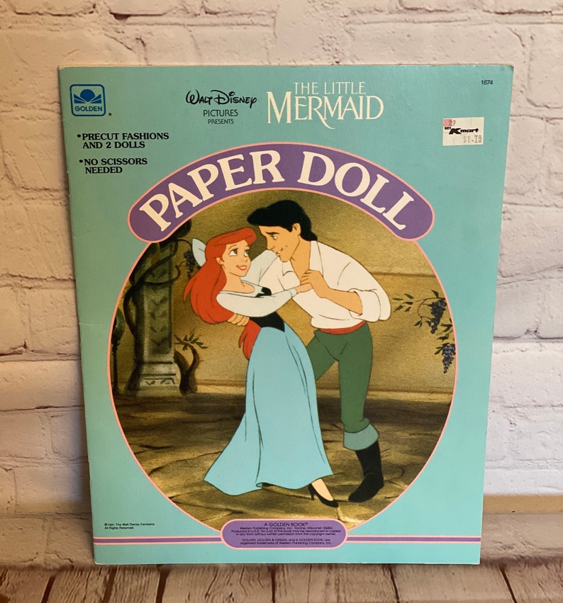 May include: A blue and pink paper doll book featuring Ariel and Prince Eric from Disney's The Little Mermaid. The book includes precut fashions and two dolls. The cover features a scene of Ariel and Eric dancing.